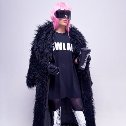 Person wearing a black fur coat, black dress with 'SWLAG' text, pink wig, and silver high boots on a white background